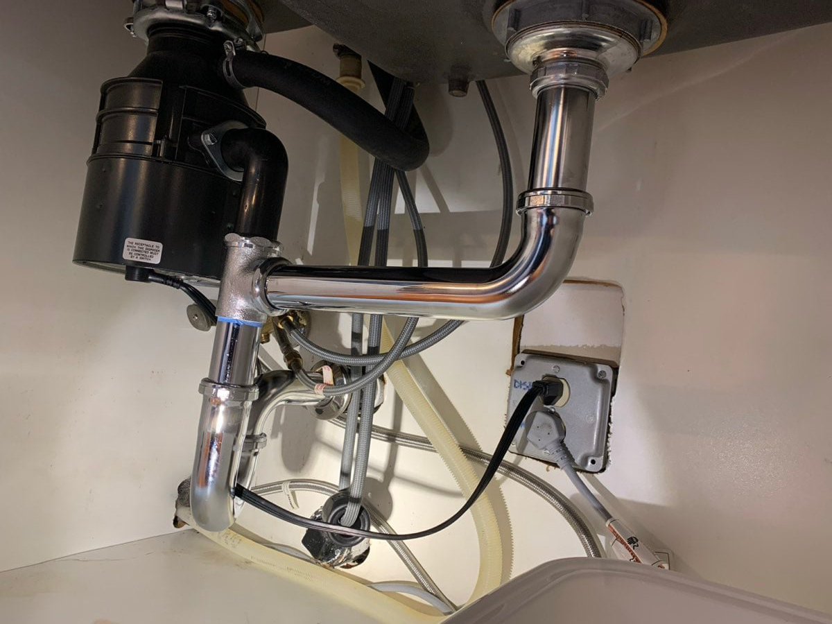 Garbage disposal with chrome drain piping installed under a sink