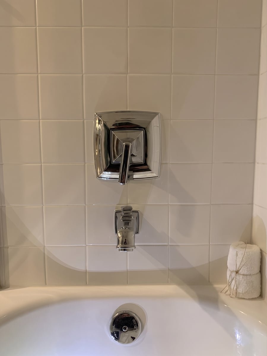 New chrome tub and shower valve trim in a tiled surround