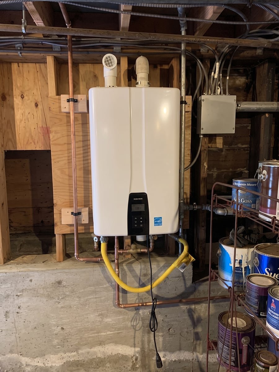 Tankless water heater mounted in a basement with new copper and gas flex