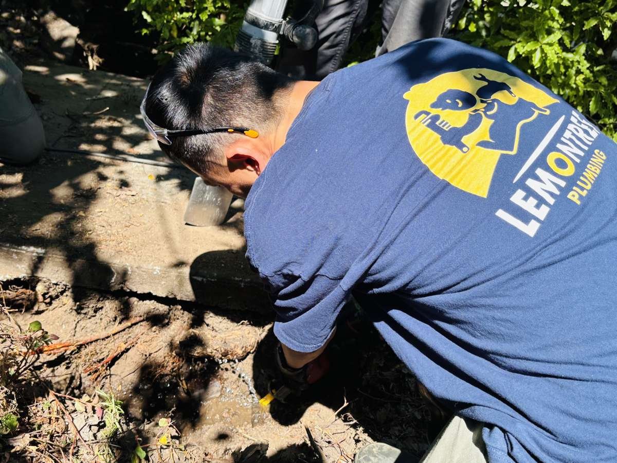 Technician repairing a leaking water service line in an excavated strip