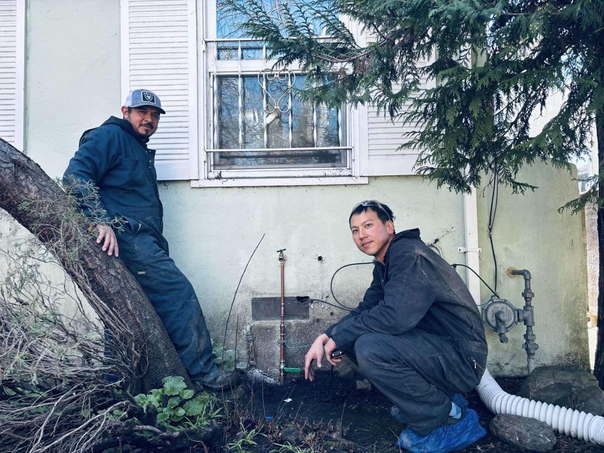 Two technicians at an exterior water service repair